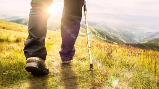 Person in Fruehpension am Wandern auf dem Gras in den Bergen.